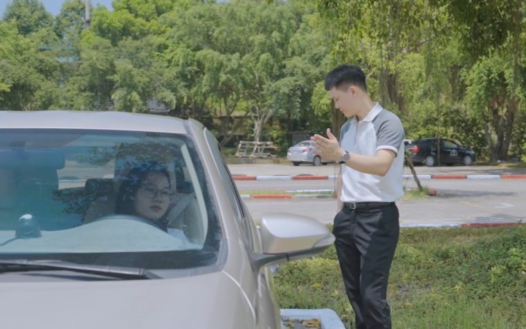 Giáo viên trao đổi với học viên bên cạnh xe tập lái tại sân